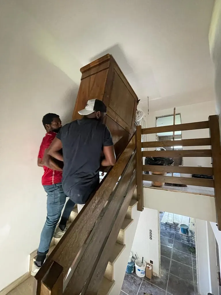 Zwei Helfer tragen einen Schrank die Treppe hinauf