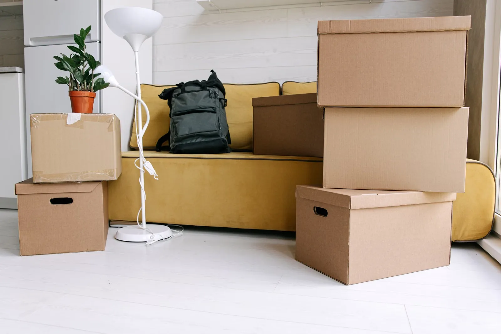 Kartons, Rucksack und Stehlampe in einer kleinen Wohnung